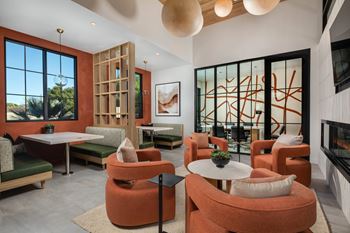 A modern living room with orange chairs and a fireplace.